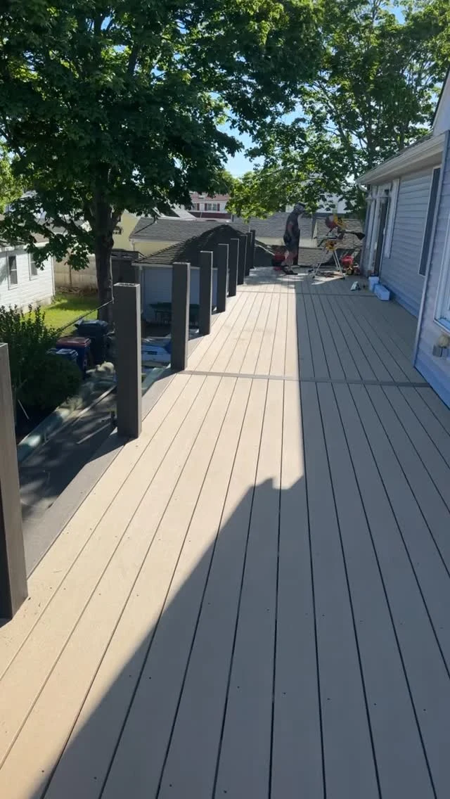 TH Finish Carpentry Instagram photograph of a deck with light boards and dark railing posts